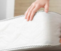 Woman putting soft orthopedic mattress on bed